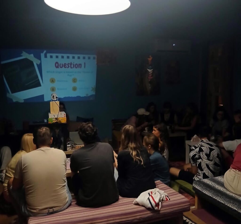 Erasmus students taking part in the ESN HMU Crete Quiz Night, with a quiz question projected on the screen